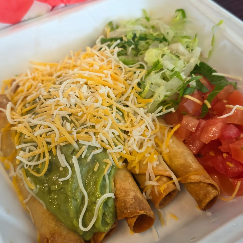 Cali Burrito Mexican Grill's taquitos topped with guacamole, shredded cheese, lettuce, and diced tomatoes.