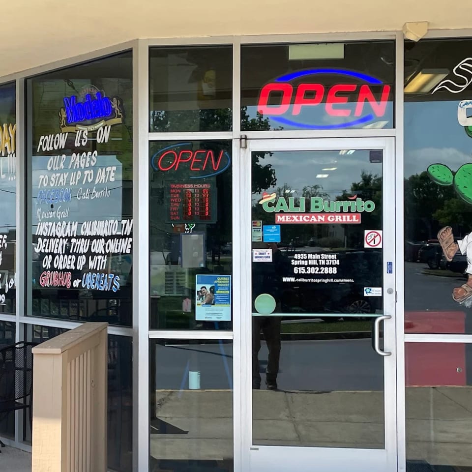 Exterior view of Cali Burrito Mexican Grill storefront with 'OPEN' signs and business information on the windows.