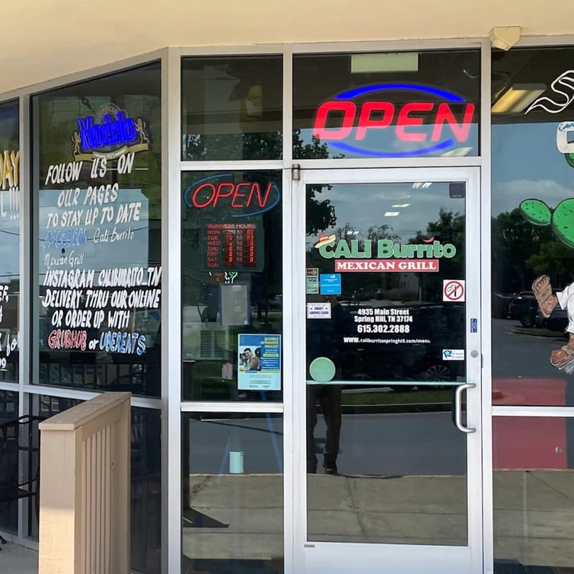 Exterior view of Cali Burrito Mexican Grill storefront with 'OPEN' signs and business information on the windows.