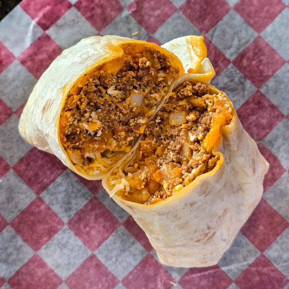 A Cali Burrito, cut in half, revealing a hearty filling of meat, cheese, and rice.